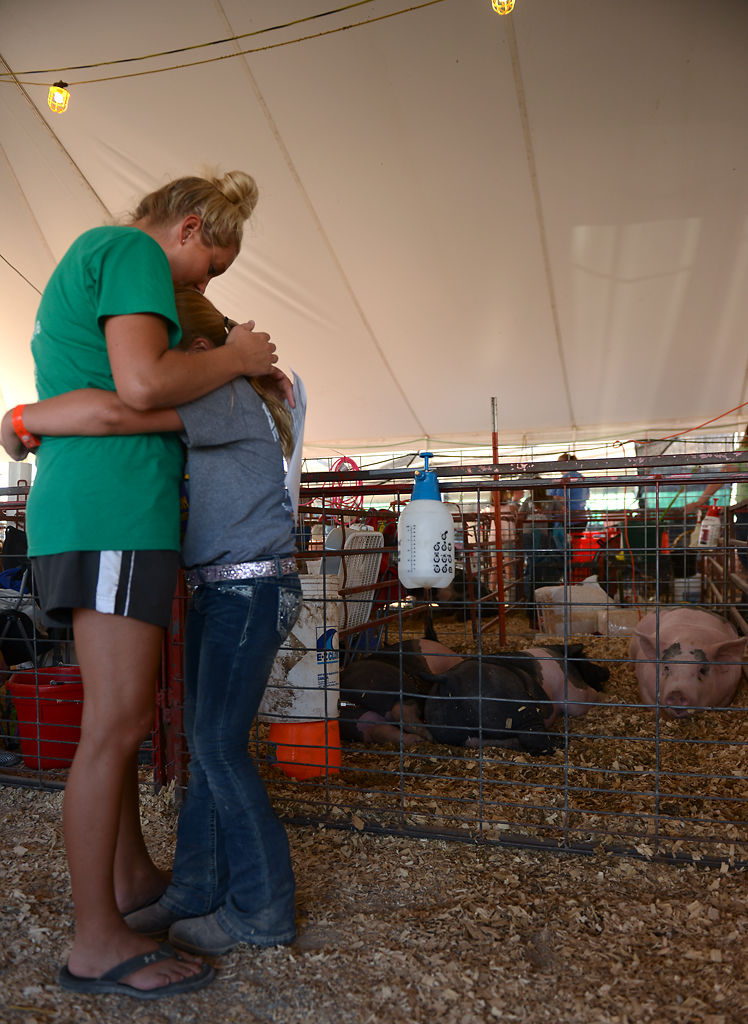 Payton Clark hugs her mom after the auctioning her pig